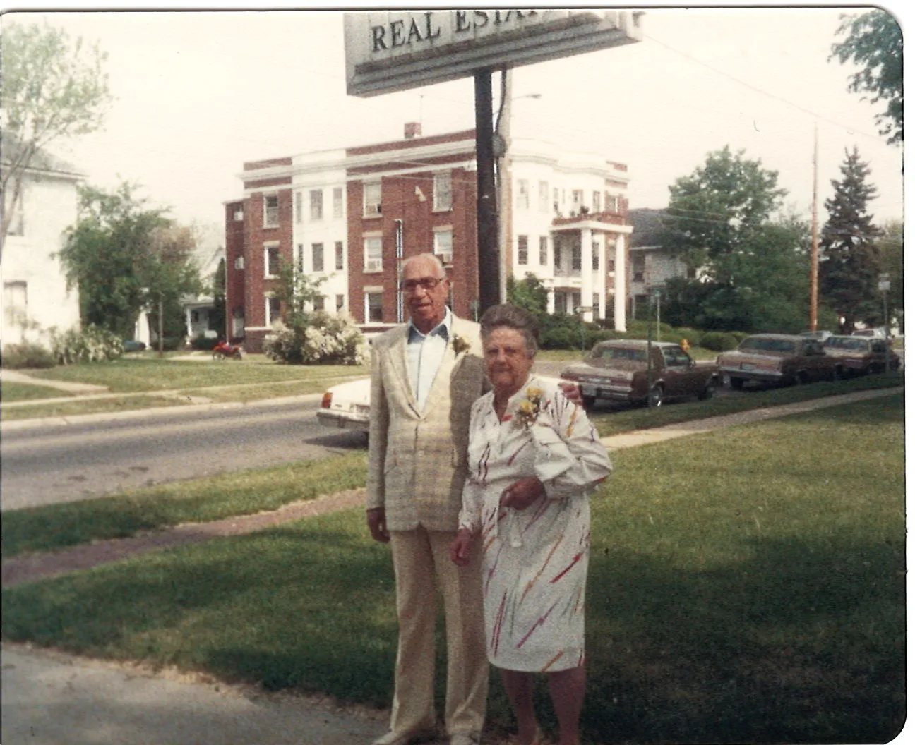 An elderly man and woman outside beneath a sign