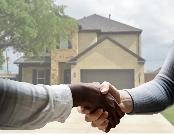 Close up of people shaking hands in front of a house